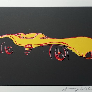 May include: Pop art print of a yellow race car with red wheels and accents against a black background. The artwork is signed and numbered 26/100. The style is reminiscent of Andy Warhol's work.