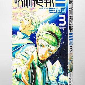 May include: A Japanese manga volume titled "Jujutsu Kaisen" with the number 3 prominently displayed. The cover features two anime-style characters with green hair and blue and white clothing. The title and other Japanese text are visible.