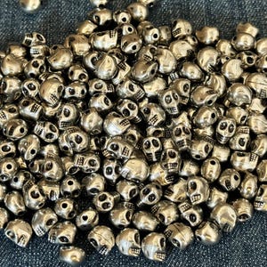 25 mini-dödskallar, enfärgade medalj- och silverfärgade kopplingsdelar, distanser, berlocker, smyckestillbehör, rocker, vintage-stil, minimalistiska dödskallar. Snyggt!