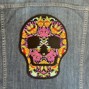 May include: A colorful embroidered skull patch with pink, yellow, and green floral designs. The skull is black and has a detailed design.