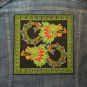 May include: A black embroidered patch with two green dragons with red and yellow accents. The dragons are curled around each other and are surrounded by a yellow and green border.