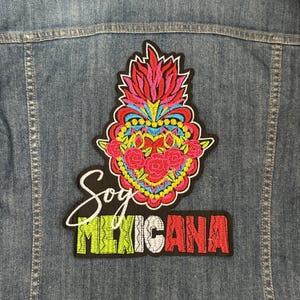 May include: A denim jacket with an embroidered patch featuring a colorful heart with flowers and the text "Soy Mexicana".