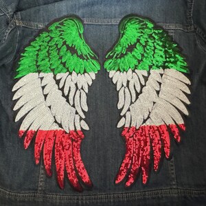 May include: A pair of sequined wings in the colors of the Italian flag, green, white, and red, are sewn onto a denim jacket.