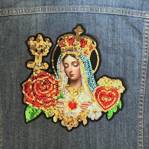 May include: A sequined iron-on patch featuring a depiction of the Virgin Mary with a crown, holding a heart and surrounded by roses. The patch is made of colorful sequins and beads.