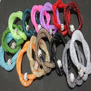 May include: Assortment of colorful stretchy bracelets with rhinestone accents. Each bracelet is made of a sparkly, woven mesh material and features a magnetic clasp.