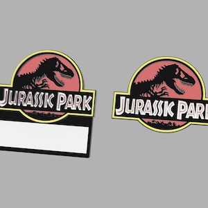 Puede incluir: Dos etiquetas de nombre con el logotipo de Jurassic Park en negro y amarillo, con una silueta de dinosaurio roja. La etiqueta de nombre de la izquierda tiene una placa de nombre blanca en blanco.