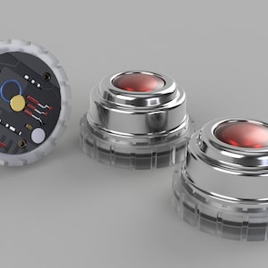 Puede incluir: Tres botones redondos de color plateado con un centro rojo translúcido. Un botón tiene un diseño de placa de circuito negro y blanco en la parte superior.