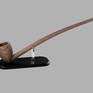 May include: A wooden pipe with a long, curved stem, resting on a black stand with a clear acrylic support.
