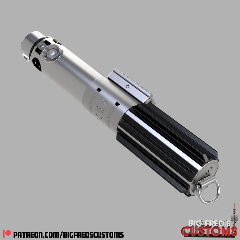 Pode incluir: Um sabre de luz prateado com um cabo preto e um emissor prateado. O cabo tem um padr&atilde;o de listras pretas e um anel prateado com a palavra "ALEX" gravada. O sabre de luz tem um la&ccedil;o preto na ponta do cabo.