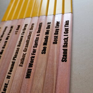 Puede incluir: Un conjunto de diez l&aacute;pices de madera con diferentes lemas grabados. Los l&aacute;pices est&aacute;n pintados de amarillo en la mitad superior y de madera natural en la mitad inferior. Los lemas incluyen "Lost... If Found Please Return To Greg", "Father, Grandfather, Hero", "Will Work For Sprite & Donuts", "She Made Me Do It", "Best Day Ever", "Stand Back, I Got This", "Don't Act Like You're Not Working", "Me Back My Pencil!", "#1 Bad", y "T".