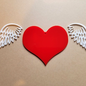 May include: A red heart with white wings on either side. The heart is a simple shape with no details. The wings are detailed with a feathery design.