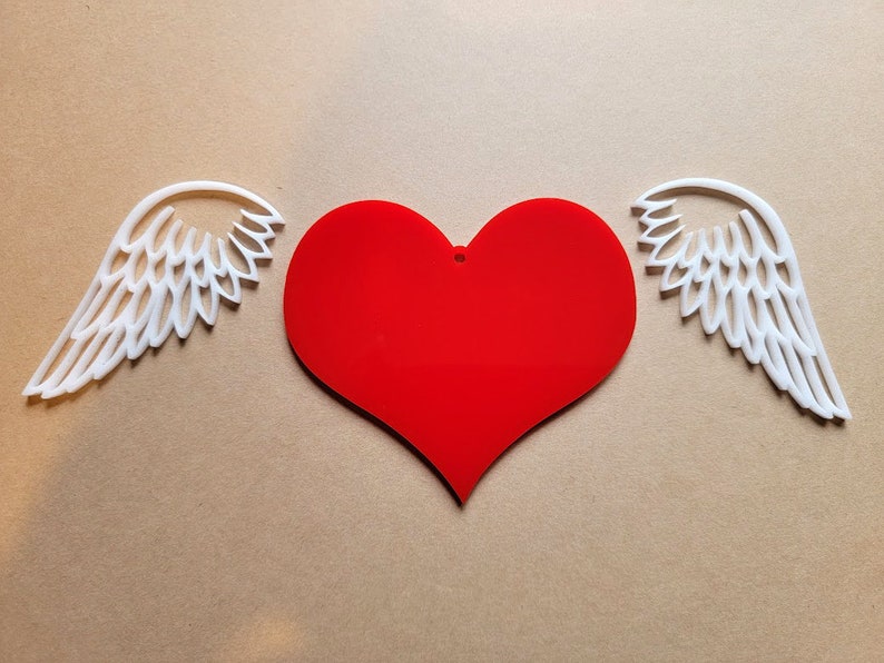 May include: A red heart with white wings on either side. The heart is a simple shape with no details. The wings are detailed with a feathery design.