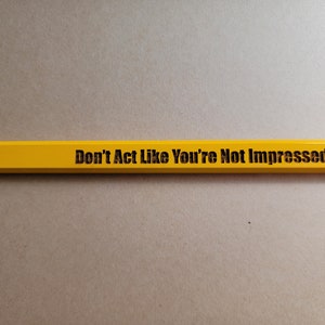 Puede incluir: Un l&aacute;piz amarillo con el texto "Don't Act Like You're Not Impressed" impreso en &eacute;l.