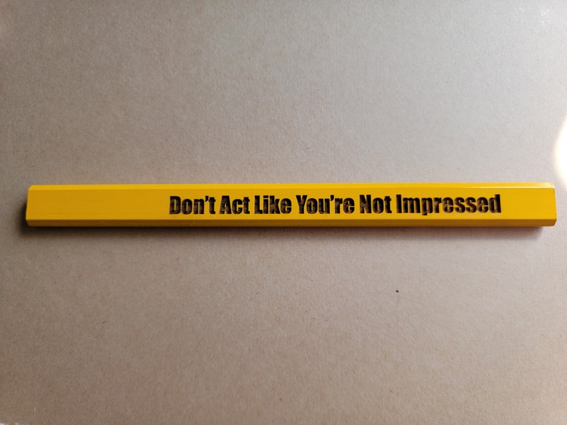 Puede incluir: Un l&aacute;piz amarillo con el texto "Don't Act Like You're Not Impressed" impreso en &eacute;l.