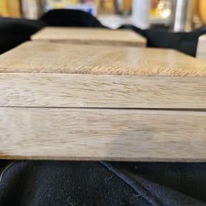 Könnte beinhalten: Eine helle Holzkiste mit einem Scharnierdeckel. Die Kiste ist aus Naturholz mit einer hellbraunen Oberfläche.