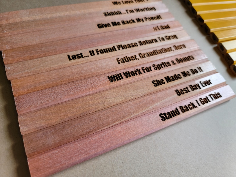 Puede incluir: Un conjunto de l&aacute;pices de madera con varios refranes humor&iacute;sticos grabados en ellos. Los refranes incluyen "We Love You", "Shaah... I'm Working", "Give Me Back My Pencil", "#1 Dad", "Lost... If Found Please Return To Gray", "Father, Grandfather, Hero", "Will Work For Sprite & Donuts", "She Made Me Do It", "Best Day Ever", y "Stand Back, I Got This".