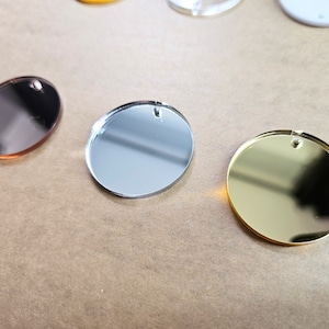 May include: Three round, mirrored acrylic discs in gold, silver, and rose gold.