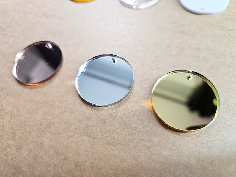 May include: Three round, mirrored acrylic discs in gold, silver, and rose gold.