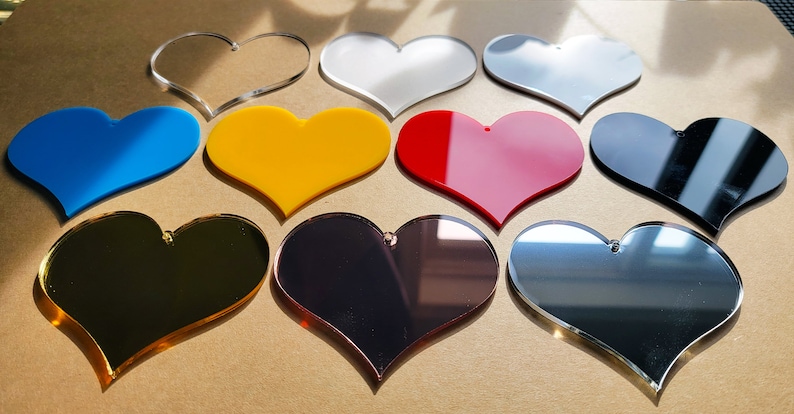 May include: Assortment of acrylic heart shapes in various colors, including clear, white, silver, blue, yellow, red, black, gold, and rose gold.
