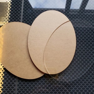 May include: Two round, brown, wooden discs and a clear, round, glass disc. The wooden discs are slightly larger than the glass disc.
