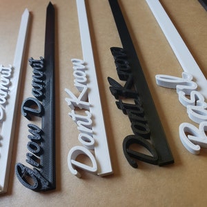 May include: Five white and black plant markers with the words "Grow Dwarf", "Grow Dwarf", "Don't Know", "Don't Know", and "Basil" written on them.