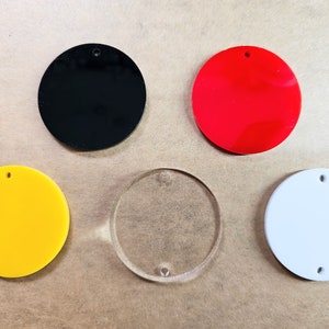 May include: Five round blank acrylic ornaments, one each in black, red, yellow, clear, and white.