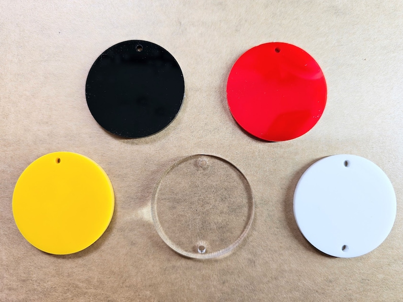 May include: Five round blank acrylic ornaments, one each in black, red, yellow, clear, and white.