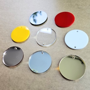 May include: Eight round, blank, acrylic circles with a hole in the center. The circles are in various colors, including red, yellow, white, silver, and gold.