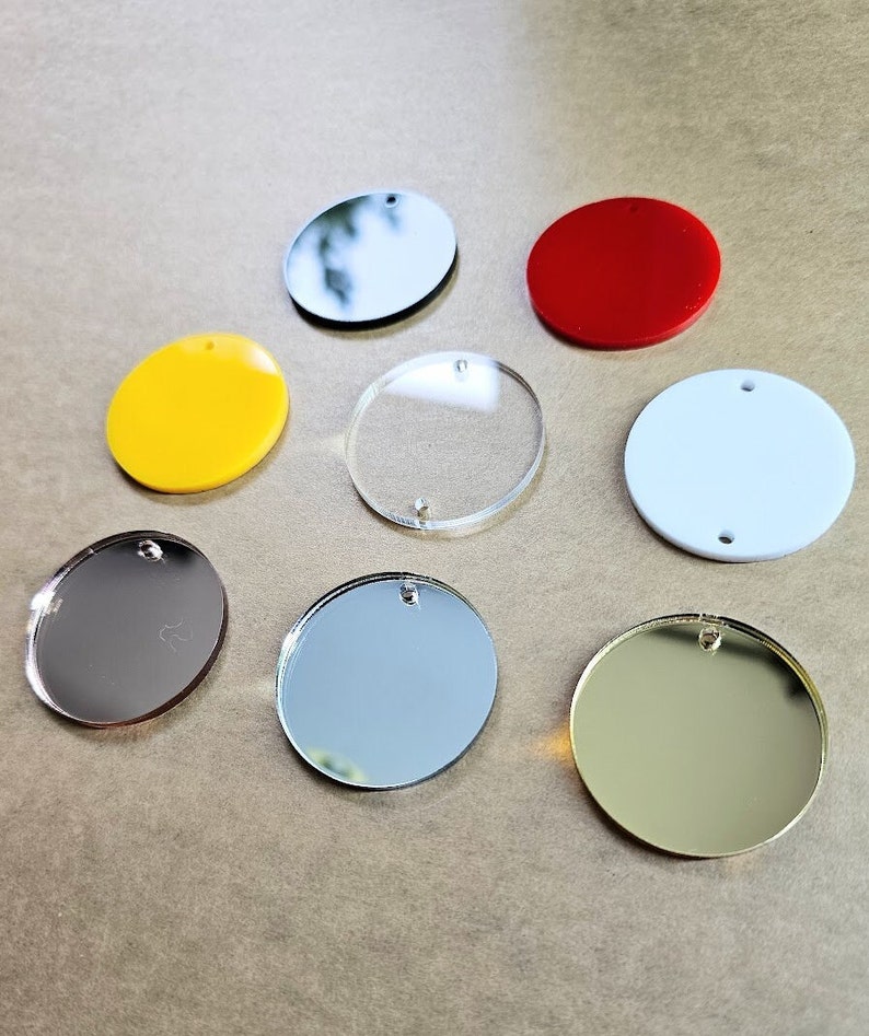 May include: Eight round, blank, acrylic circles with a hole in the center. The circles are in various colors, including red, yellow, white, silver, and gold.
