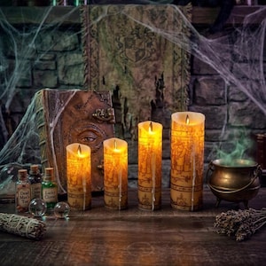 May include: Four cylindrical LED candles with warm yellow light and printed illustrations of figures in robes, featuring faux wax drips. Beside them are three small glass bottles labeled Lucky Man's Toe and Lucky Clovet, a small metal cauldron, and a book.