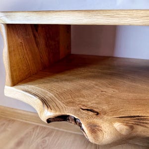 May include: A wooden wall shelf with a natural live edge design. The shelf has a single open compartment and a smooth, light brown finish.