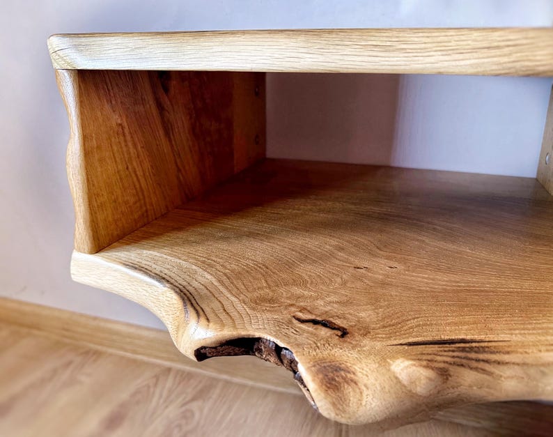 May include: A wooden wall shelf with a natural live edge design. The shelf has a single open compartment and a smooth, light brown finish.