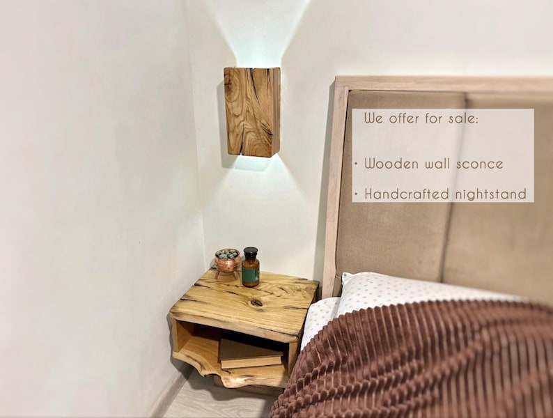 May include: A wooden nightstand with a shelf and a small wooden wall sconce above it. The nightstand is next to a bed with a brown blanket. The text on the headboard reads: "We offer for sale: Wooden wall sconce Handcrafted nightstand"