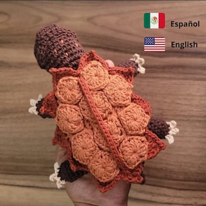 Puede incluir: Juguete de amigurumi de tortuga tejido a crochet con cabeza marrón y caparazón naranja. El caparazón está hecho de múltiples círculos tejidos a crochet.