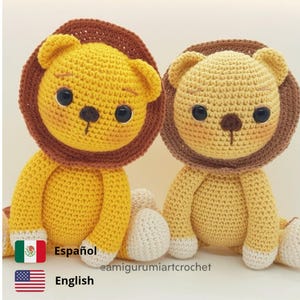 May include: Two crocheted lion plushies, one yellow and one light brown, sitting side-by-side. Both have brown manes and white feet. The plushies have black eyes and brown noses. The text "@amigurumiartcrochet" is visible below the plushies.