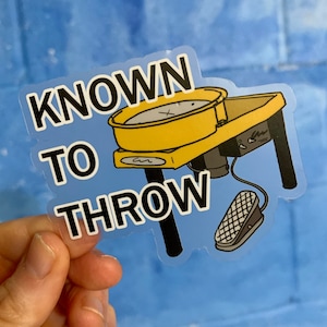 May include: A yellow pottery wheel with a black base and foot pedal. The wheel has a black cord and a white label that says "Known to Throw".