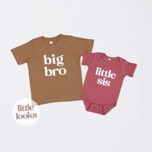 May include: Two brown and pink short-sleeved shirts with the text "big bro" and "little sis" in white. The shirts are on a white background.