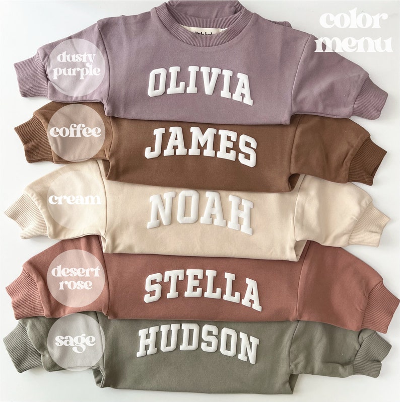 May include: Five crewneck sweatshirts in different colors with names embroidered in white on the front. The colors are dusty purple, coffee, cream, desert rose, and sage.