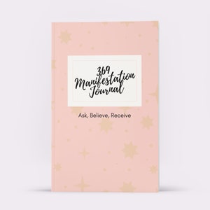 May include: A pink journal with a white rectangle containing the text "369 Manifestation Journal" and the text "Ask, Believe, Receive" below the rectangle. The background of the journal is a pink and gold star pattern.