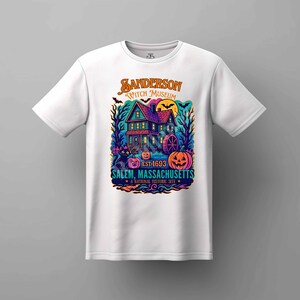 May include: White t-shirt featuring a colorful graphic of a haunted house with the text "Sanderson Witch Museum EST. 1693 Salem, Massachusetts". The design includes pumpkins, a black cat, and a full moon, evoking a Halloween theme.