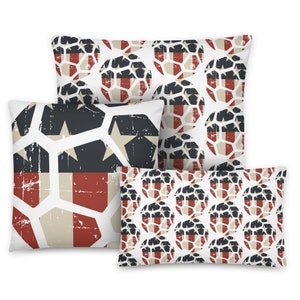 May include: Four decorative throw pillows with a distressed patriotic design. The pillows feature a white background with patterns in red, navy, and tan. One pillow has a star and stripe design, while others have a geometric pattern.