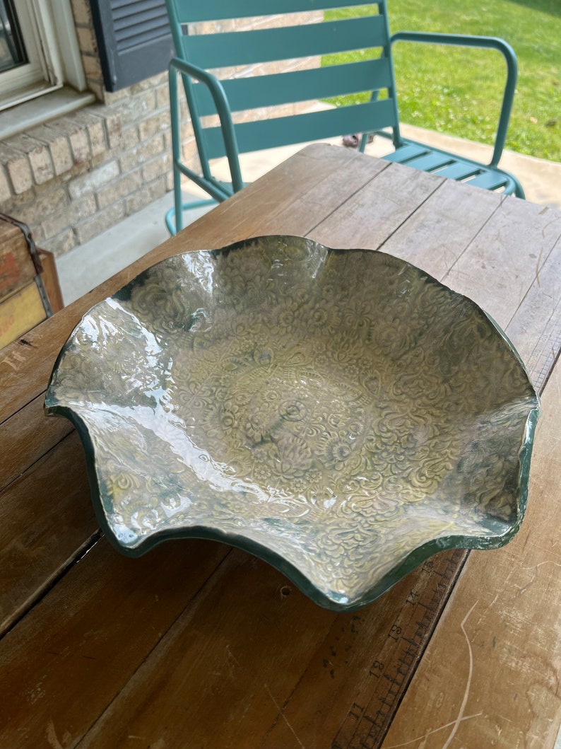 May include: A large, scalloped ceramic serving dish with a white glaze and a green and white floral pattern.