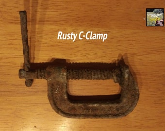 May include: A rusty C-clamp, a tool used for holding work pieces together. The clamp is made of metal and shows signs of age and wear. The text "Rusty C-Clamp" is visible in the image.