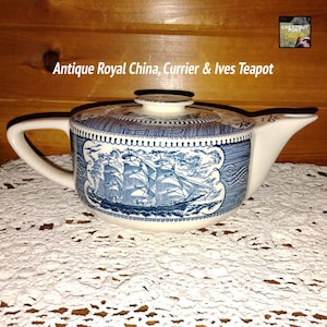 May include: Antique Royal China, Currier & Ives teapot. The white teapot features a blue and white nautical scene with a sailing ship. The lid and handle are white. The text "Antique Royal China, Currier & Ives Teapot" is above the teapot.
