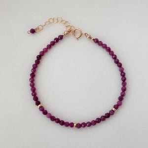 Peut inclure: Un bracelet délicat en chaîne dorée avec de petites pierres précieuses violettes facettées. Le bracelet est doté d'un fermoir à homard.
