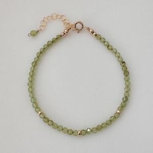 May include: A delicate gold bracelet featuring green gemstone beads. The bracelet has a simple clasp and is ideal for everyday wear.