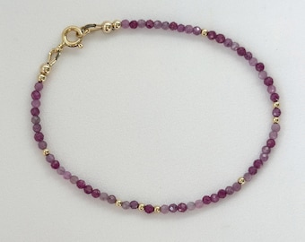 May include: A delicate bracelet made with small purple gemstone beads and gold accents. The bracelet has a simple clasp closure.