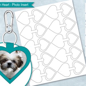 May include: A teal heart-shaped keychain with a photo insert. The keychain has a silver ring and a silver clasp. The photo insert shows a small dog with brown and white fur. The image also shows a sheet of paper with multiple heart-shaped outlines.