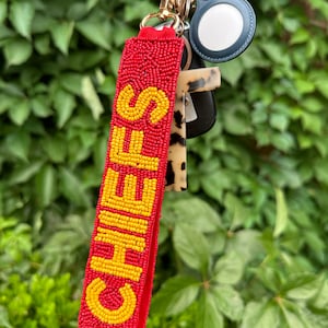 May include: Red beaded keychain with the word "CHEERS" spelled out in yellow beads.