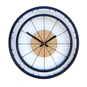 May include: A black and white clock with a wooden center and a white background. The clock face is designed to look like a bicycle wheel.
